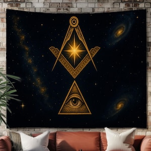 May include: A large black tapestry featuring a gold Masonic symbol design against a starry night sky. The design includes a compass, square, and an all-seeing eye within a triangle. The tapestry is displayed above a red sofa in a living room setting.