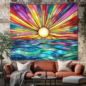 Op de afbeelding: Een kleurrijk wandkleed met een zonsopgang in de stijl van een glas-in-loodraam boven een blauwe zee. De zon is geel en de lucht is een mix van roze, oranje, geel en paars.