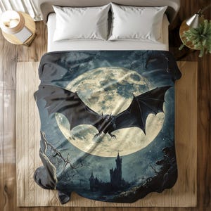 May include: A dark blue and grey blanket with a large, full moon and a black bat flying in front of it. The moon has a light yellow glow and the bat has sharp teeth and claws. The background is a dark forest with a castle in the distance.