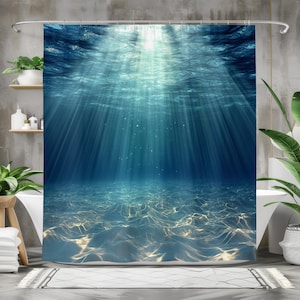 May include: A blue shower curtain with a photo of the ocean floor. The photo shows sunlight shining through the water and onto the sandy bottom.