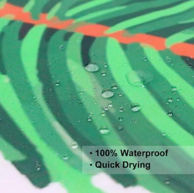 Puede incluir: Primer plano de una cortina de ducha de tela con estampado de hojas tropicales verdes y blancas. Hay gotas de agua en la tela, lo que demuestra las caracter&iacute;sticas impermeables y de secado r&aacute;pido de la cortina de ducha.