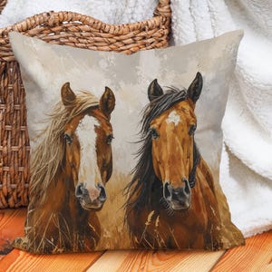May include: Square throw pillow featuring a watercolor painting of two horses. The horses have brown coats, with one having a white blaze and blonde mane, and the other with a dark mane. The background is a neutral beige.