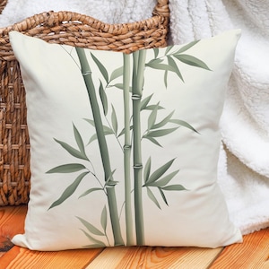 May include: A white throw pillow with a green bamboo design. The pillow is on a light brown wooden surface.