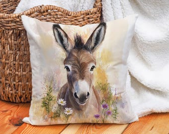 May include: A watercolor painting of a donkey with brown and white fur. The donkey is looking directly at the viewer with its head tilted slightly to the side. The background is a soft yellow with watercolor splashes of blue and green. There are small purple flowers in the foreground.
