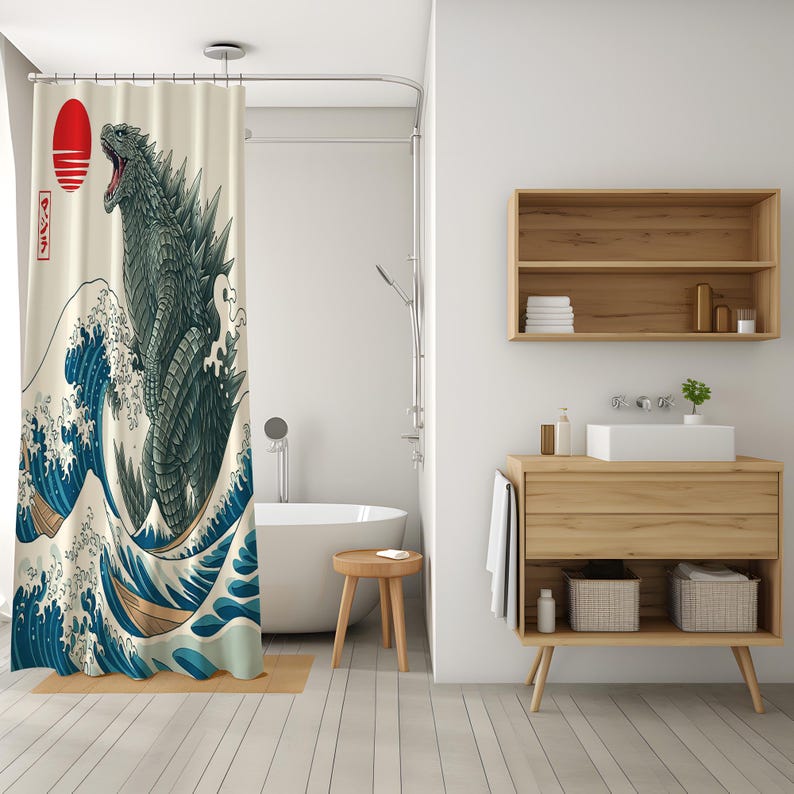 May include: A shower curtain featuring a Godzilla design in the style of Hokusai's "The Great Wave off Kanagawa." The artwork depicts Godzilla emerging from ocean waves, with a red sun and Japanese text in the upper left corner. The color palette includes shades of blue, green, and beige.
