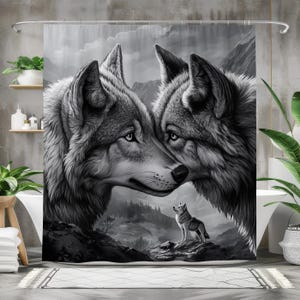 Op de afbeelding: Een zwart-witte douchegordijn met een close-up van twee wolven met hun hoofden tegen elkaar. De wolven kijken naar een kleinere wolf in de verte. De achtergrond is een wazige bos scène.