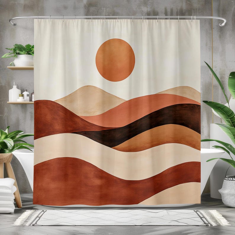 May include: A shower curtain with an abstract landscape design. The artwork shows rolling hills in shades of brown, beige, and black, with a large orange sun in the sky. The curtain hangs from a silver rail in a bathroom setting.