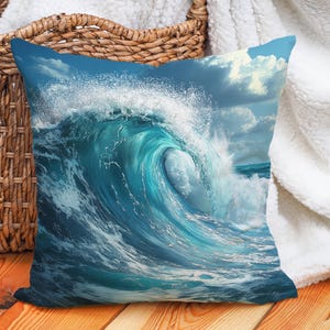 Pode incluir: Uma almofada azul e branca com uma foto de uma grande onda oceânica quebrando. A onda é azul turquesa com espuma branca.