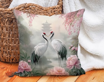 May include: A decorative throw pillow with a watercolor design of two white cranes standing in a misty garden with pink flowers and a pagoda in the background.