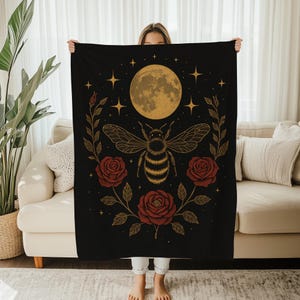 Könnte beinhalten: Schwarze Decke mit einem Bienen-Design, Vollmond, Sternen und roten Rosen. Die Biene hat detaillierte Flügel und einen gestreiften Körper. Die Rosen blühen voll und der Mond ist goldfarben. Dekoratives Heimtextil.