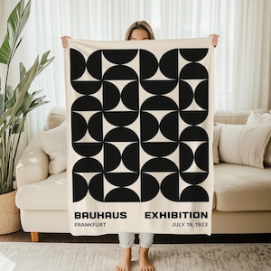 Peut inclure: Couverture crème avec un motif géométrique Bauhaus noir. La couverture présente un motif répétitif de demi-cercles et de cercles. Le texte en bas indique "BAUHAUS EXHIBITION FRANKFURT JULY 19, 1923".