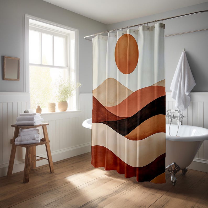 May include: A shower curtain featuring a watercolour design of a sun and layered mountain range in shades of brown, beige, and black. The curtain hangs in a bathroom with a white bathtub and wooden floor.