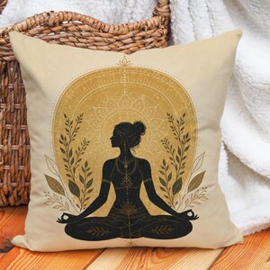 May include: A square throw cushion with a cream-coloured fabric cover featuring a black silhouette of a person in a seated meditation pose. The design includes a large golden circular mandala pattern behind the figure, flanked by leafy branches.