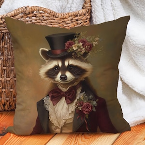 Puede incluir: Un mapache con un sombrero de copa y una chaqueta de terciopelo burdeos con un cuello de encaje blanco y una pajarita roja. El mapache tiene un arreglo floral en la cabeza y un fondo marrón.