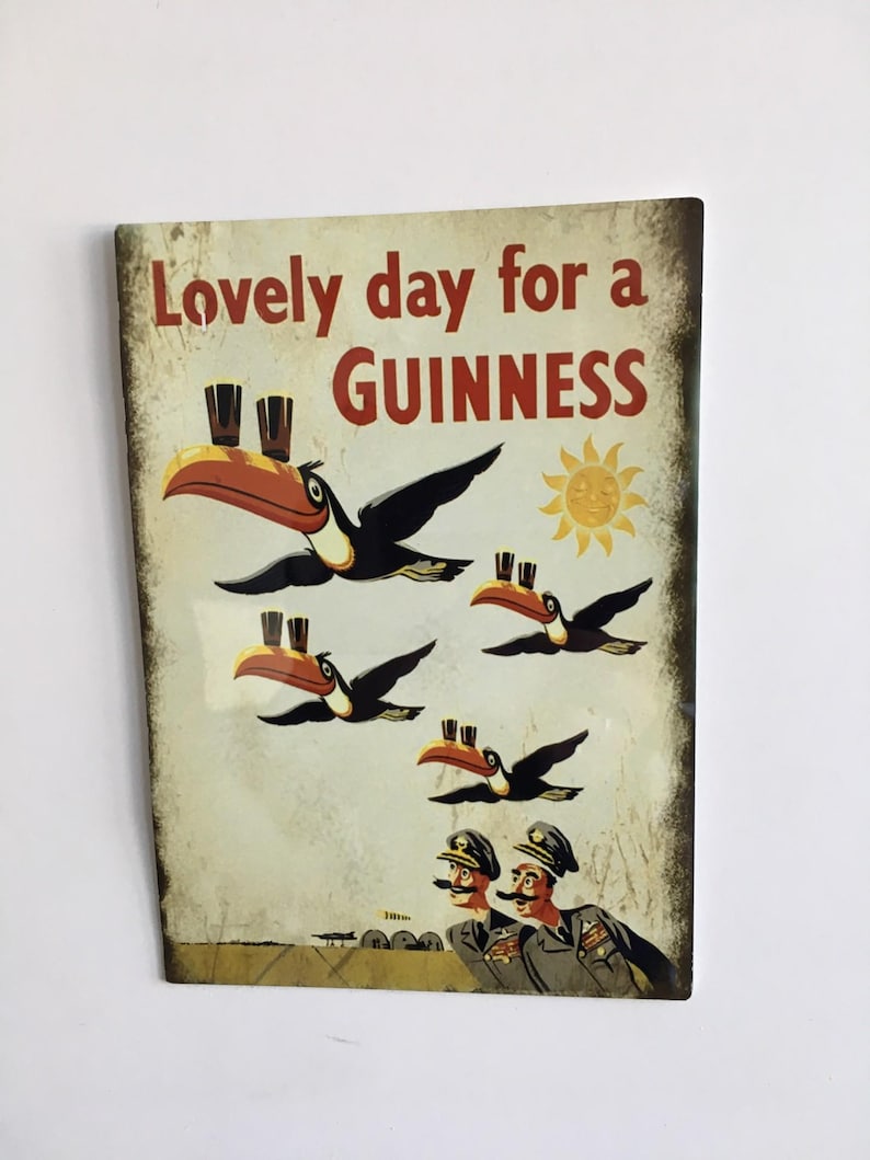 Puede incluir: Anuncio vintage de Guinness con el texto "Lovely day for a Guinness". Presenta tucanes con vasos de Guinness en sus picos, volando frente a un sol. Dos hombres uniformados con bigotes est&aacute;n en la parte inferior.
