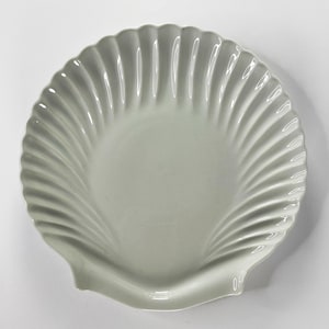 Può includere: Un piatto da portata in ceramica bianca a forma di conchiglia con bordo scanalato.