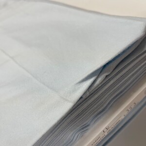 May include: A stack of light blue flannel fabric. The fabric is folded and labeled "Flannel" with the text "Yards 1 1/2  100% Cotton 45.5"