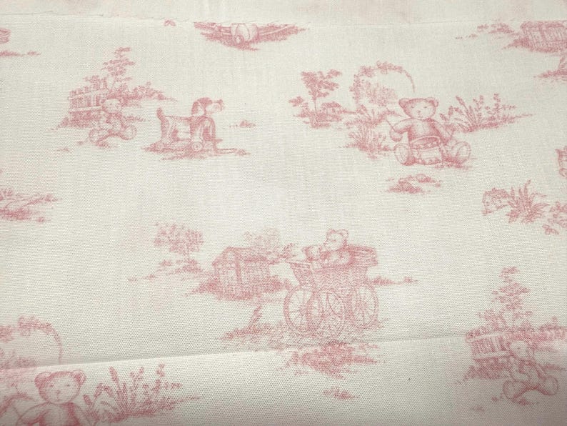 May include: White fabric with a repeating pattern of pink teddy bears, dogs, and other pastoral scenes. The design is reminiscent of a toile fabric, with a vintage or antique aesthetic. The fabric is likely cotton or linen.
