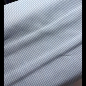 May include: A light blue fabric with a white gingham pattern. The fabric is woven and has a soft texture.