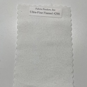 Op de afbeelding: Witte stofstaal met de tekst "Fabric Finders, Inc. Ultra-Fine Flannel #290" gedrukt op een label.