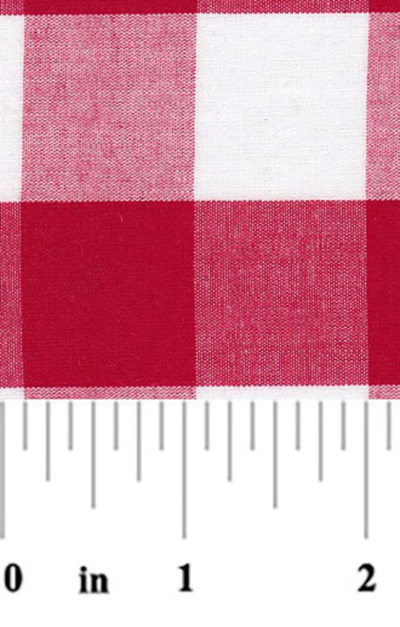 Pu&ograve; includere: Primo piano di tessuto a quadri rossi e bianchi. Il tessuto presenta un classico motivo a quadretti con grandi quadrati. Un righello &egrave; in basso, che mostra le misure in centimetri. Il tessuto viene probabilmente utilizzato per tovaglie o altri articoli per la casa.