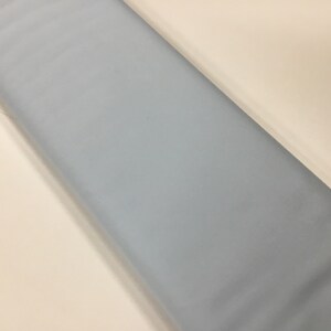 May include: A piece of light blue fabric. The fabric is smooth and has a subtle sheen.