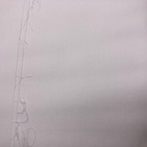 May include: Close-up of white fabric with a visible seam running vertically down the center. The fabric has a textured appearance, and loose threads are present along the seam's edge. The image highlights the texture and construction of the material.