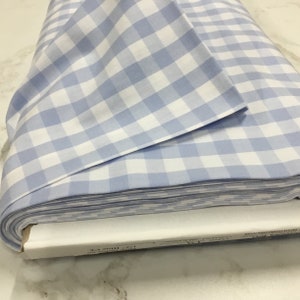 K&ouml;nnte beinhalten: Eine Rolle wei&szlig;-blau karierter Stoff. Der Stoff ist gefaltet und das Etikett lautet "1/2" Blue Gingham."