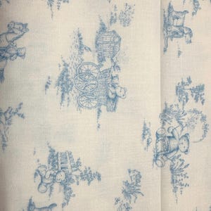 May include: Off-white fabric with a repeating blue toile pattern. The design features teddy bears, carriages, and floral elements. The fabric has a classic, vintage aesthetic, suitable for various craft projects.