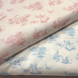 May include: Two rolls of fabric with a toile pattern. One roll features a red and white design with images of teddy bears, horse-drawn carriages, and children. The other roll has a blue and white design with similar imagery.
