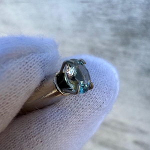May include: A silver ring with a blue gemstone set in a prong setting.
