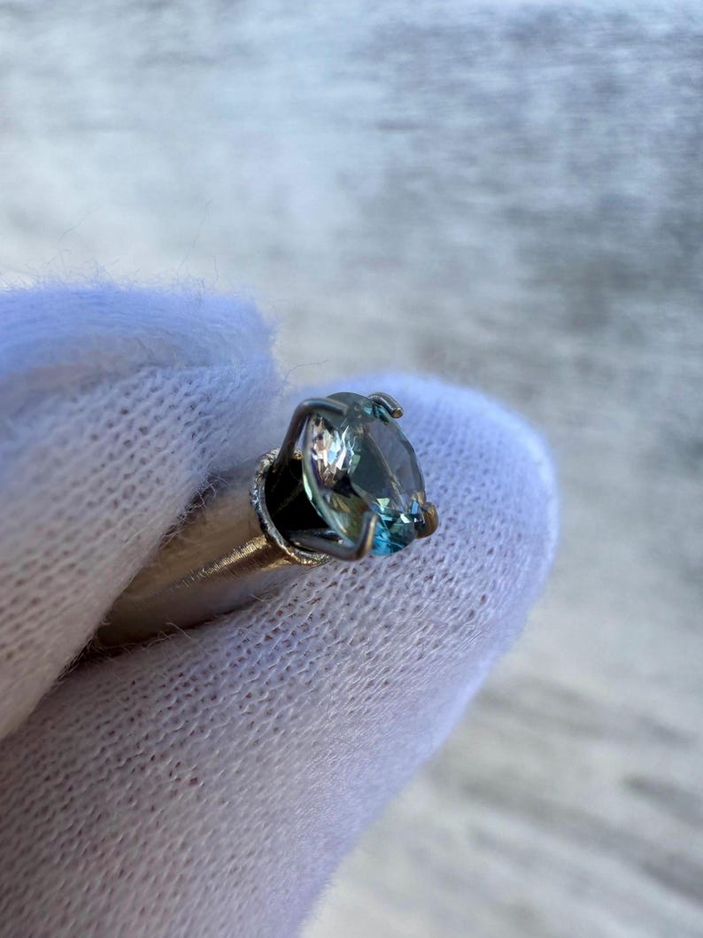 May include: A silver ring with a blue gemstone set in a prong setting.