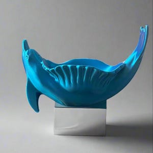 May include: A blue ceramic sculpture of a stylised fish with a silver base. The fish is curved into a bowl shape.