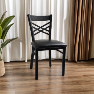 May include: Black dining chair with a criss-cross back design and a padded seat. The chair has a simple, modern style.