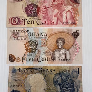 May include: Three vintage Ghanaian banknotes: a 10 Cedis note featuring a man with a pipe, a 5 Cedis note with a woman in a hat, and a 1 Cedi note with cocoa pods. Each bill displays the Bank of Ghana seal.