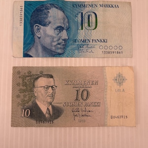 May include: Two Finnish 10 Markkaa banknotes. The top bill is blue and green, featuring a portrait and text. The bottom bill is brown and green, with a portrait and text. Both bills have the number 10 prominently displayed.