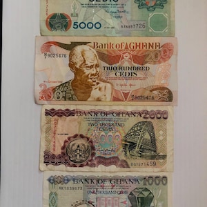 May include: Four different denominations of Ghanaian Cedi banknotes. The banknotes are in various colors, including red, green, and blue. The banknotes feature images of a bridge, a diamond, and a portrait of a man. The banknotes also feature the text "Bank of Ghana" and the denomination amount.