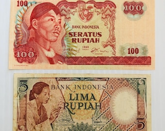 Op de afbeelding: Twee Indonesische bankbiljetten, een rode en een groene. Het rode biljet is een biljet van 100 roepia met een portret van een man en de tekst "SERATUS RUPIAH". Het groene biljet is een biljet van 5 roepia met een portret van een vrouw en de tekst "LIMA RUPIAH".