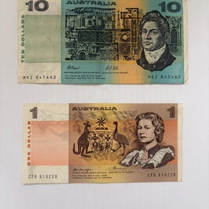 May include: Two Australian banknotes: a ten-dollar note with a portrait and building design, and a one-dollar note featuring a kangaroo and emu with a portrait. Both notes have serial numbers.