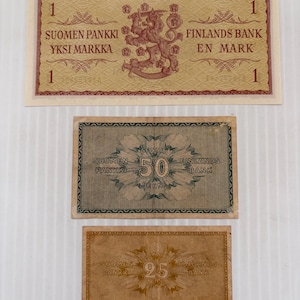 May include: Three vintage Finnish banknotes. The top note is a one markka bill with text in Finnish and Swedish, featuring a lion emblem. Below are a 50 penni and a 25 penni note.
