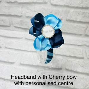 May include: Blue and navy blue headband with a large bow and a personalised centre that says "Lexy May".