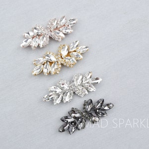 Puede incluir: Cuatro pares de clips para zapatos de cristal en diferentes colores: plateado, dorado, transparente y negro. Los clips tienen forma de racimo de hojas y están adornados con diamantes de imitación.