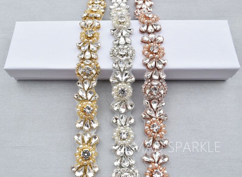 May include: Three beaded trims with floral designs in gold, silver, and rose gold. Each trim features a repeating pattern of rhinestones and pearls.