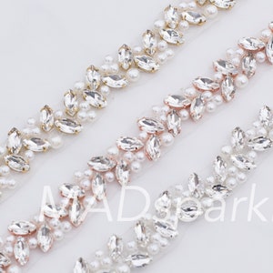 May include: Three rows of white, gold, and rose gold beaded trim with clear rhinestones. The trim is on a white background.