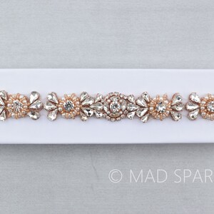 May include: A rose gold beaded and rhinestone trim with clear and pearlescent stones. The trim is on a white background.
