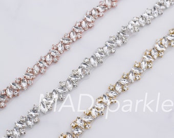 May include: Three rows of clear rhinestone trim with different colored metal settings. The top row has rose gold settings, the middle row has silver settings, and the bottom row has gold settings.