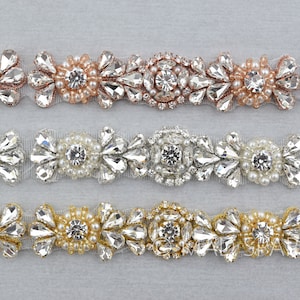 May include: Three rows of beaded trim with different colored beads. The top row has rose gold beads, the middle row has white beads, and the bottom row has gold beads. All three rows have clear rhinestones.