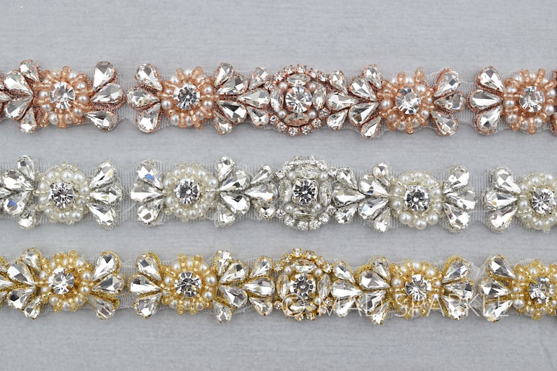 May include: Three rows of beaded trim with different colored beads. The top row has rose gold beads, the middle row has white beads, and the bottom row has gold beads. All three rows have clear rhinestones.