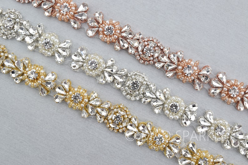 May include: Three rows of beaded trim with clear rhinestones and pearls. The top row is rose gold, the middle row is silver, and the bottom row is gold.
