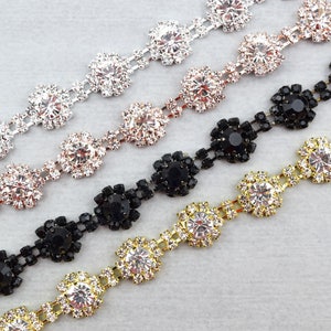 May include: Four strands of rhinestone chain trim with different colored settings. The chains feature round, faceted rhinestones in silver, gold, rose gold, and black settings.